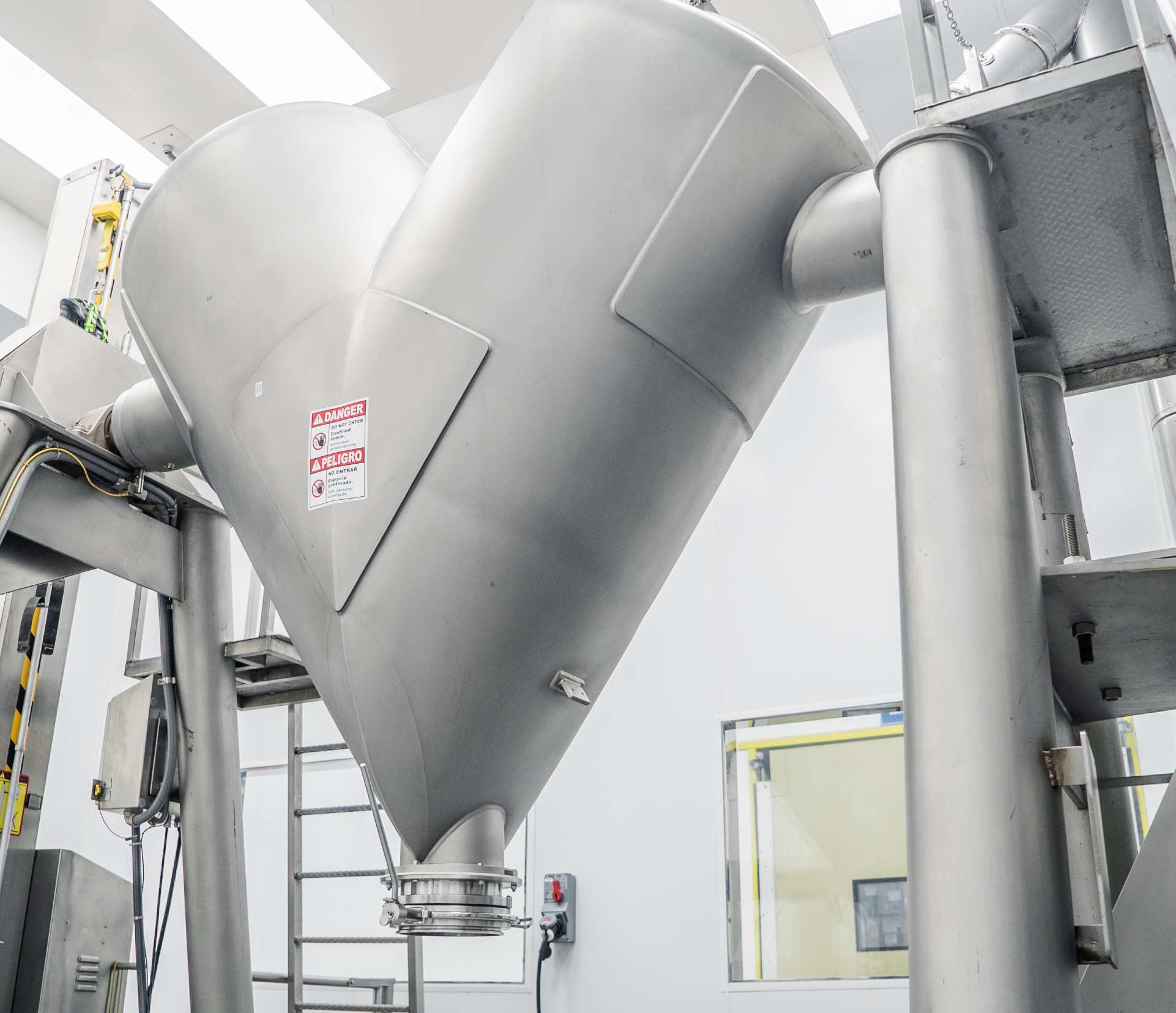 A large metal V-Blender in a bright room